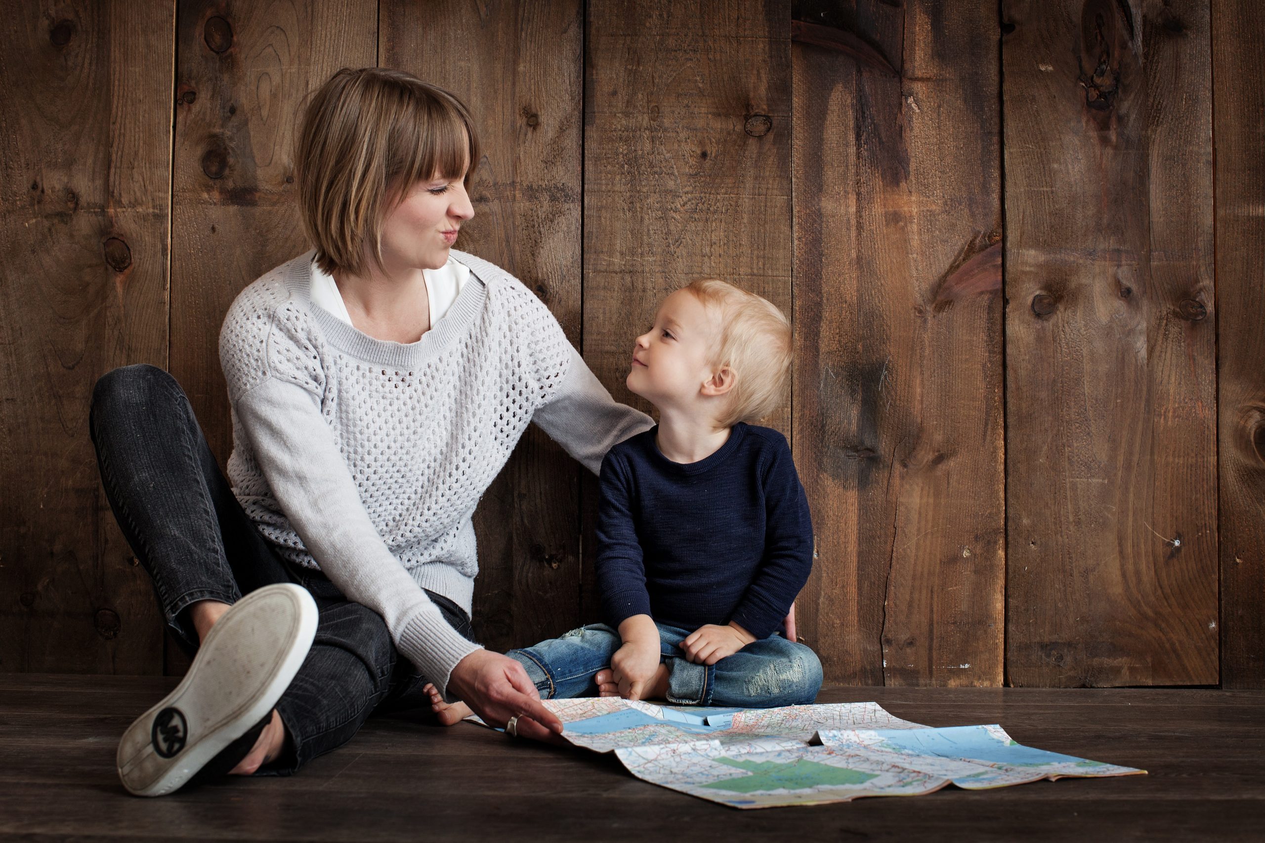 woman sitting on the floor with a toddler, holding a map